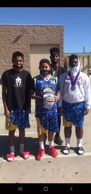 Custom sublimated basketball shorts in blue, gold, and white design, with matching v-neck jersey available for custom team order