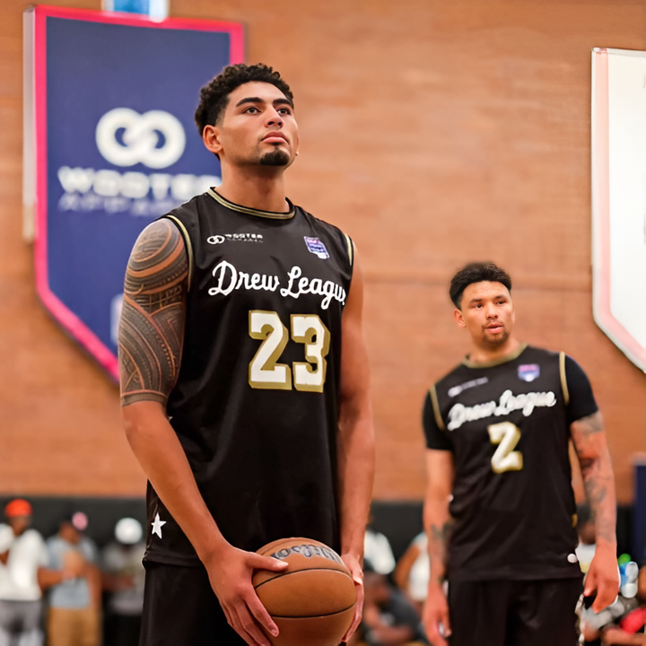 Basketball players wearing black custom uniforms during a competitive indoor game.