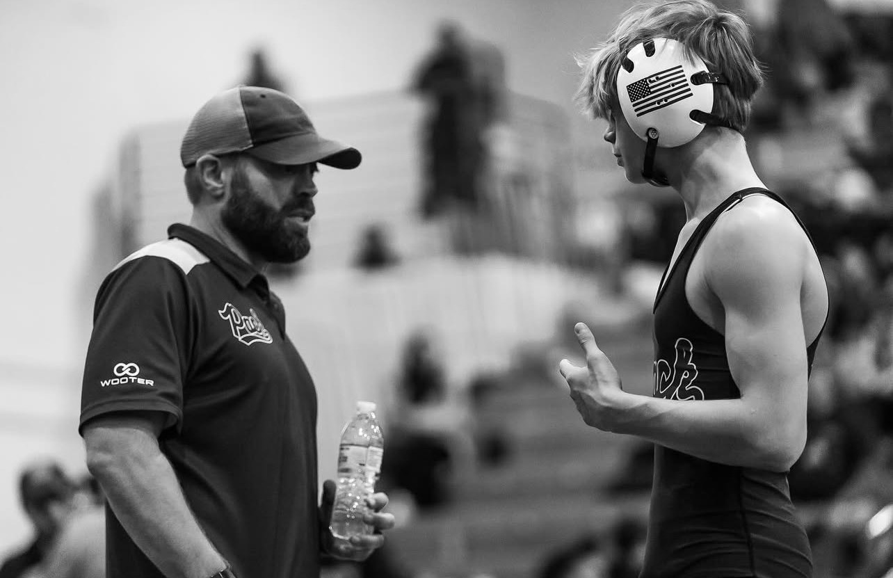 Coach talking with athlete in Wooter gear