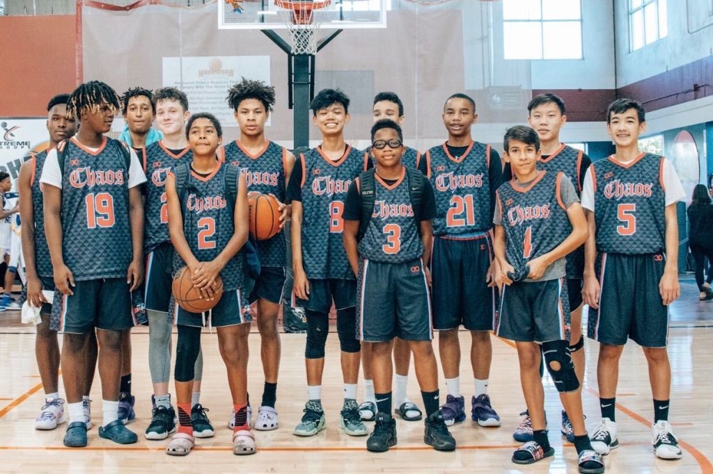 Youth basketball team posing in matching custom uniforms with player numbers on court
