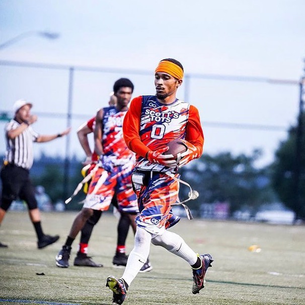 7v7 flag football player running with the ball wearing a custom uniform and flag belt