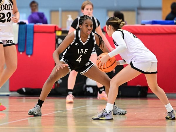 Girls basketball players competing in a fast-paced indoor game while wearing custom team uniforms.